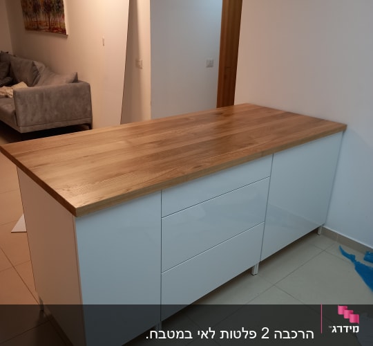 אי מטבח עם משטח עץ ודלתות לבנות